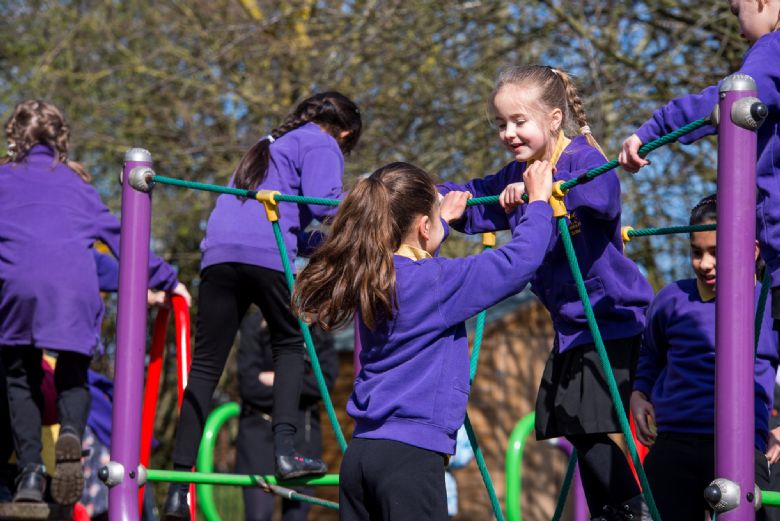  pupils play together on outdoor play equipment